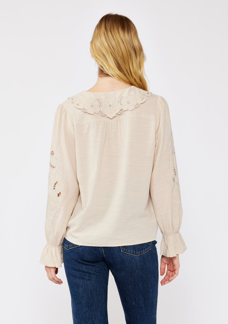 [Color: Buff] A blonde model wearing a beige blouse with a peter pan collar. A relaxed fit bohemian blouse with tonal embroidery, hook and eye front closure, long sleeves, and ruffle trim cuffs.