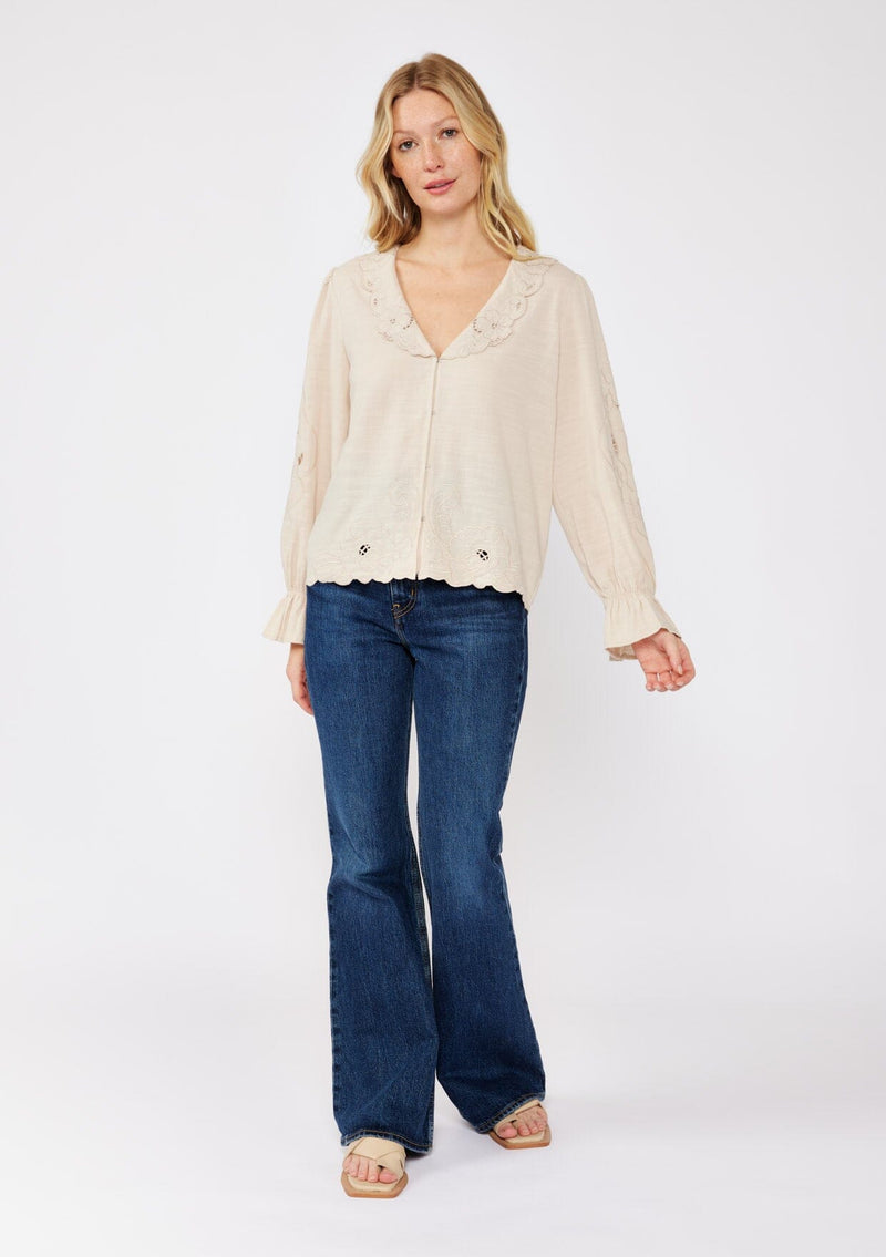 [Color: Buff] A blonde model wearing a beige blouse with a peter pan collar. A relaxed fit bohemian blouse with tonal embroidery, hook and eye front closure, long sleeves, and ruffle trim cuffs.