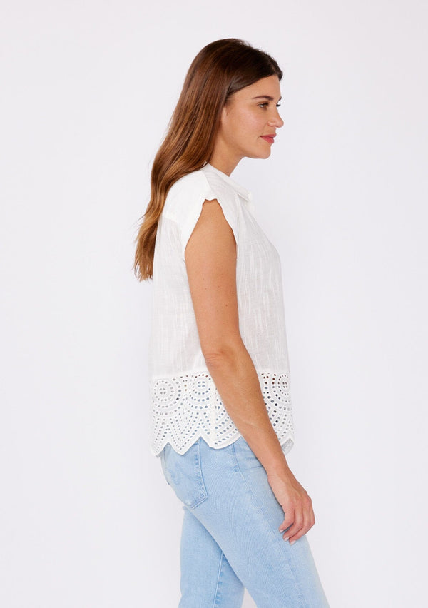 [Color: White] A brunette model wearing a breezy cotton camp shirt with a unique embroidered eyelet design and scalloped edge. This white collared top features a functional button front, cap sleeves, and a relaxed fit. Paired with light wash denim jeans for that effortless summer style.