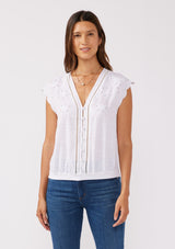 [Color: White] A front facing image of a brunette model wearing a rayon and cotton blend top with an embroidered floral cutout design. This casual white top features a v neckline, button front, short dolman sleeves, and a hip hugging elastic hem at the back. 