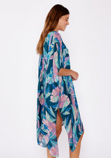 [Color: Teal/Dusty Orchid] A brunette model wearing a blue and pink tropical inspired palm leaf print kimono. A lightweight kimono perfect for the beach or to style a casual outfit. With an open front, mid length , half kimono sleeves, and side vents.