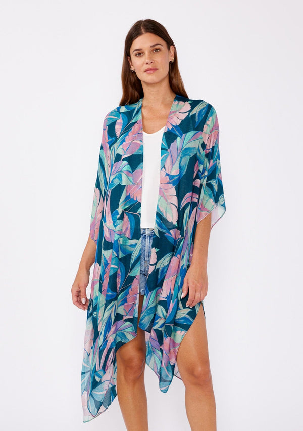 [Color: Teal/Dusty Orchid] A brunette model wearing a blue and pink tropical inspired palm leaf print kimono. A lightweight kimono perfect for the beach or to style a casual outfit. With an open front, mid length , half kimono sleeves, and side vents. 