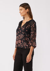 [Color: Black/Dusty Rose] A side facing image of a brunette model wearing a sheer chiffon black blouse with a pink floral print. A lightweight top featuring a button front, split v neckline, and 3/4 length sleeves. Ideal for special occasions and holiday events. 