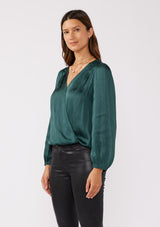 [Color: Teal] A side facing image of a brunette model wearing a holiday green silky polyester satin top. This special occasion top features a surplice v neckline, front hook and eye closure, elastic hemline, and long sleeves. Perfect for Christmas and holiday parties. 