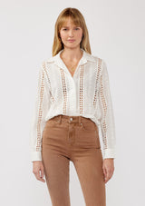 [Color: White] A front facing image of a blonde model wearing floral eyelet shirt with a collared neckline, button front, and long sleeves with button cuffs. A sophisticated spring top paired with brown denim bottoms for spring. 