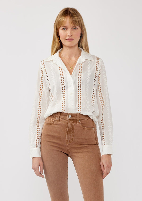 [Color: White] A front facing image of a blonde model wearing floral eyelet shirt with a collared neckline, button front, and long sleeves with button cuffs. A sophisticated spring top paired with brown denim bottoms for spring. 