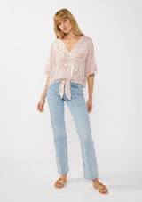 [Color: Natural/Dusty Pink] A front facing image of a blonde model wearing a pink bohemian print blouse with a v-neckline, tie front detail at the hem, and flowy kimono sleeves. Perfect for resort styling and casual outings. 