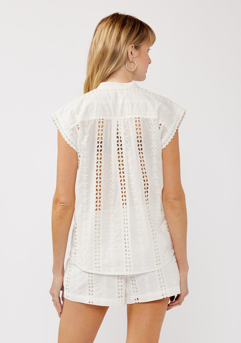 [Color: White] A back facing image of a blonde model wearing a white striped eyelet embroidered camp shirt with a button front and short dolman sleeves. Styled for the beach and a resort vacation getaway. 