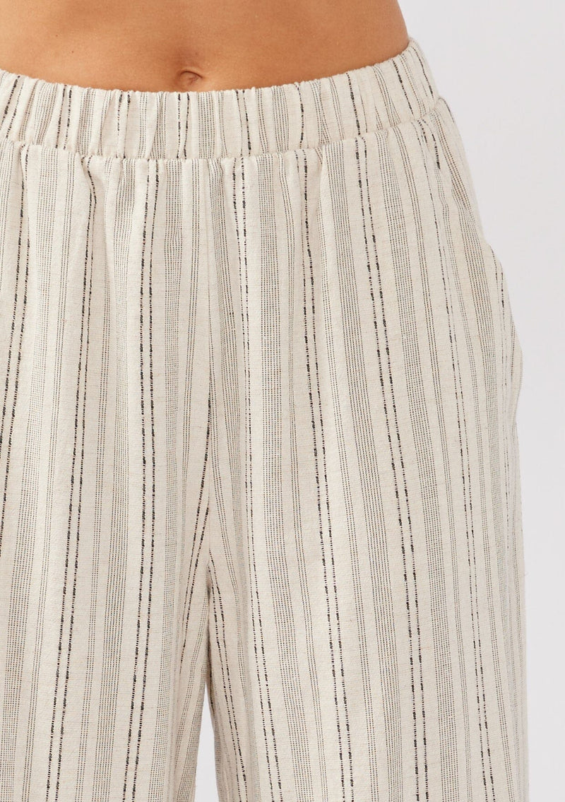 [Color: Natural/Black] A detail image of a model wearing beige cotton-blend pants with black yarn-dyed stripes. The pants feature an elastic waistband, wide legs, and a cropped hem, making them perfect for vacation, lounging, or a beach cover-up.