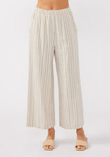 [Color: Natural/Black] An image of a model wearing beige cotton-blend pants with black yarn-dyed stripes. The pants feature an elastic waistband, wide legs, and a cropped hem, making them perfect for vacation, lounging, or a beach cover-up.