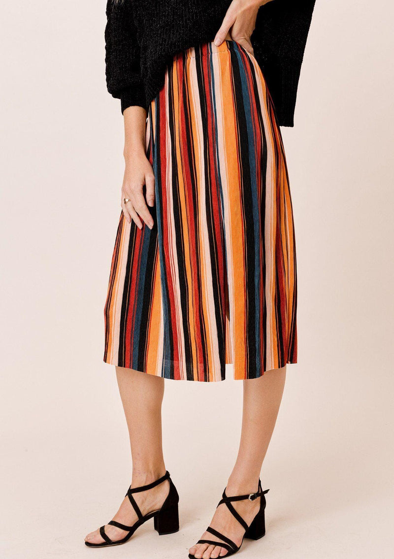 [Color: Black/Spice/Teal:] A blonde wearing a colorful pleated midi skirt with an elastic waistband and front slit. Perfectly versatile, this vertical stripe skirt is styled with a cozy sweater for a laid back look, perfect for the Fall season. 