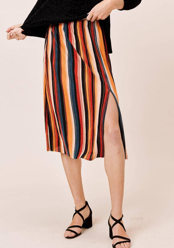 [Color: Black/Spice/Teal:] A blonde wearing a colorful pleated midi skirt with an elastic waistband and front slit. Perfectly versatile, this vertical stripe skirt is styled with a cozy sweater for a laid back look, perfect for the Fall season. 