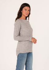 [Color: Heather Grey] A side facing image of a brunette model wearing a high neckline pullover sweater with long sleeves and ribbed details. 