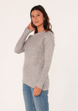 [Color: Heather Grey] A side facing image of a brunette model wearing a high neckline pullover sweater with long sleeves and ribbed details. 