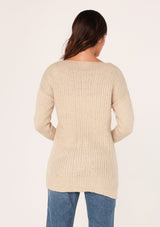 [Color: Natural] A back facing image of a brunette model wearing a high neckline pullover sweater with long sleeves and ribbed details. 