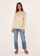 [Color: Natural] A front facing image of a brunette model wearing a high neckline pullover sweater with long sleeves and ribbed details. 