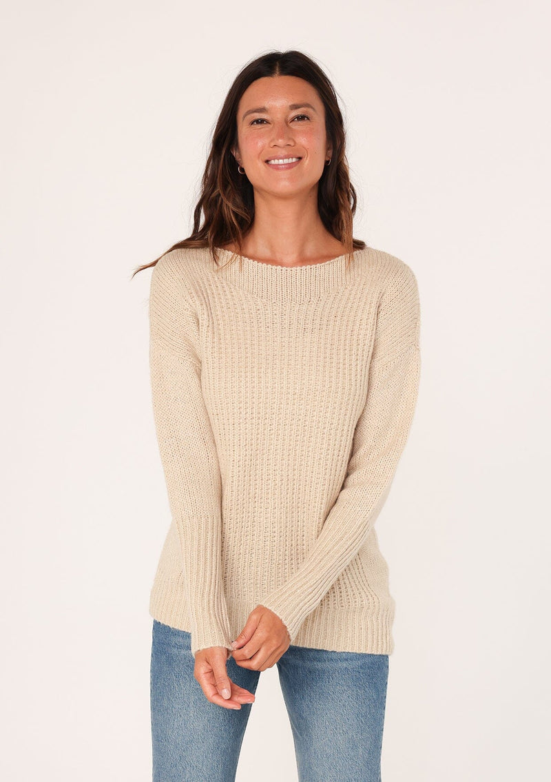 [Color: Natural] A front facing image of a brunette model wearing a high neckline pullover sweater with long sleeves and ribbed details. 