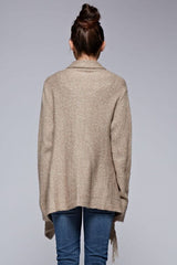 [Color: Taupe] A back facing image of a brunette model wearing a cozy one-sided fringe sweater cardigan with a versatile wrap front. This asymmetrical sweater features two side buttons for easy draping and securing the wrap silhouette. 