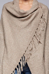 [Color: Taupe] A detail image of a brunette model wearing a cozy one-sided fringe sweater cardigan with a versatile wrap front. This asymmetrical sweater features two side buttons for easy draping and securing the wrap silhouette. 