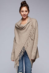 [Color: Taupe] A front facing image of a brunette model wearing a cozy one-sided fringe sweater cardigan with a versatile wrap front. This asymmetrical sweater features two side buttons for easy draping and securing the wrap silhouette. 