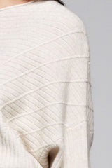 [Color: Oatmeal] A detail image of a brunette model wearing an off white ribbed sweater with cozy long dolman sleeves. 