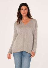 [Color: Heather Grey] A front facing image of a brunette model wearing a cozy grey pullover sweater with a v-neckline, ribbed long sleeves, dropped shoulders, and side vents. The perfect throw on for fall styling. 