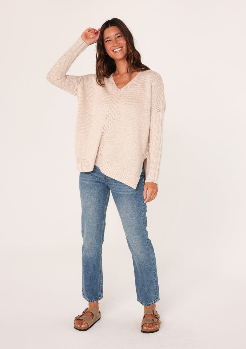 [Color: Heather Petal] A front facing image of a brunette model wearing a cozy grey pullover sweater with a v-neckline, ribbed long sleeves, dropped shoulders, and side vents. The perfect throw on for fall styling. 