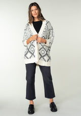 [Color: Ivory/Black] A brunette model wearing a diamond knit pattern cardigan with an open front, 3/4 length sleeves, and a ribbed trim. A cozy knit throw on for the Fall season. 