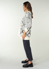 [Color: Ivory/Black] A brunette model wearing a diamond knit pattern cardigan with an open front, 3/4 length sleeves, and a ribbed trim. A cozy knit throw on for the Fall season. 