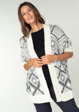 [Color: Ivory/Black] A brunette model wearing a diamond knit pattern cardigan with an open front, 3/4 length sleeves, and a ribbed trim. A cozy knit throw on for the Fall season. 