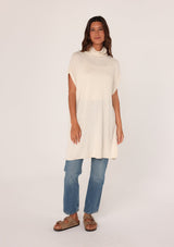 [Color: Oatmeal] A front facing image of a brunette model wearing a off white funnel neck tunic sweater with short dolman sleeves, a long hemline, and side slits. The perfect lightweight sweater tunic for layering or wearing on its own as a dress. 