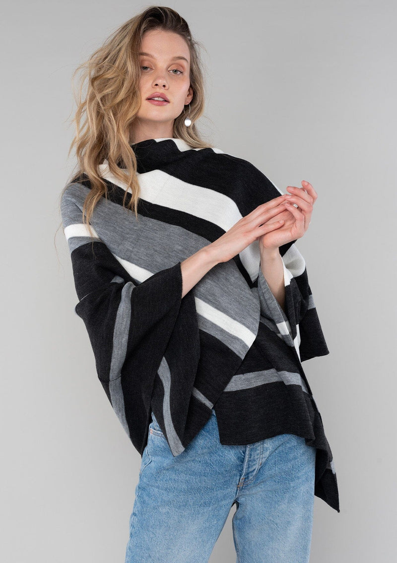 [Color: Charcoal Combo] A blonde model wearing a charcoal combo multi-stripe poncho with an open front, asymmetrical hemline, and a casual, effortless drape in soft acrylic knit.