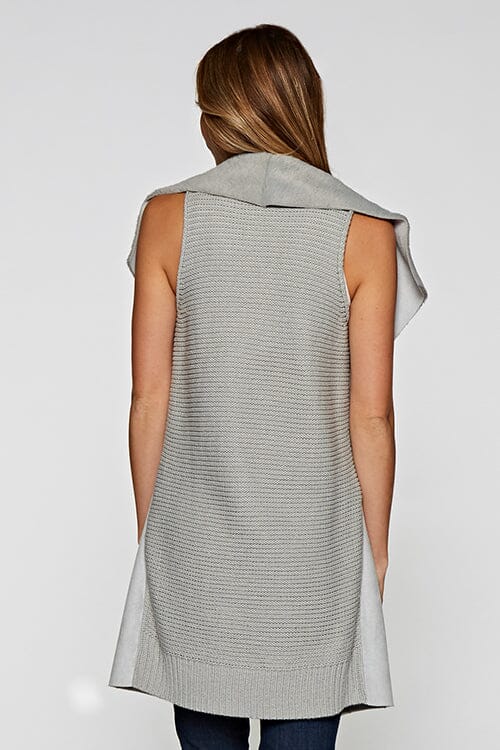 [Color: Grey] A blonde model wearing a casual grey vegan suede vest with a faux fur trim interior and contrasting ribbed knit back. 