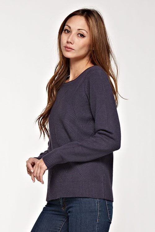 [Color: Graphite] A side facing image of a brunette model wearing a cozy ribbed knit sweater with a geometric design and a round neckline. 