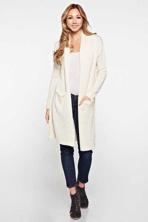 [Color: Vanilla] A blonde model wearing a cream ivory cardigan with a shawl collar, patch pockets, and a distressed back detail. 