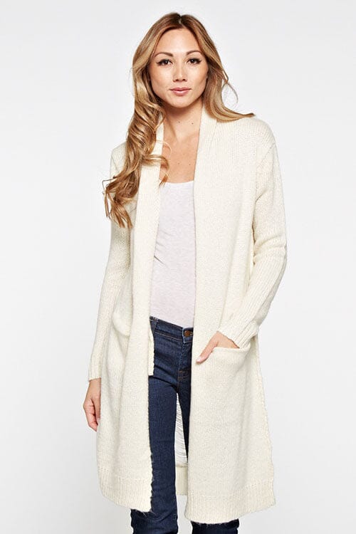 [Color: Vanilla] A blonde model wearing a cream ivory cardigan with a shawl collar, patch pockets, and a distressed back detail. 