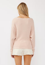 [Color: Heather Blush] A back facing image of a blonde model wearing a light pink waffle knit pullover sweater. With long sleeves, a relaxed fit, and a wide neckline that can be worn off the shoulder.