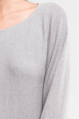 [Color: Heather Ash] A detail image of a brunette model wearing a relaxed fit pullover grey sweater with long dolman sleeves, a round neckline, and a fitted hem. A long torso sweater perfect for casual outings and lounging. 