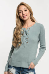 [Color: Pistachio] A blonde Asian model wearing a mint green pullover sweater featuring a lace-up front and grommet details. This waffle knit sweater is a versatile addition to any fall wardrobe, perfect for everyday wear.