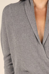 [Color: Heather Ash] A grey waffle knit cross front sweater. Featuring long dolman sleeves, a sexy cross front detail, and a flattering shawl collar that can be worn off the shoulder. Paired here with denim for a classic and chic Fall look. 