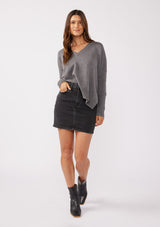 [Color: Heather Charcoal] A front facing image of a brunette model wearing a soft and relaxed fit knit sweater in gray. A cozy fall pullover sweater with a boxy silhouette, v neckline, ribbed trim, and side vents. 