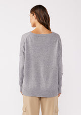 [Color: Lt. Heather Grey] A back facing image of a brunette model wearing a soft and relaxed fit knit sweater. A cozy fall pullover sweater with a boxy silhouette, v neckline, ribbed trim, and side vents. 