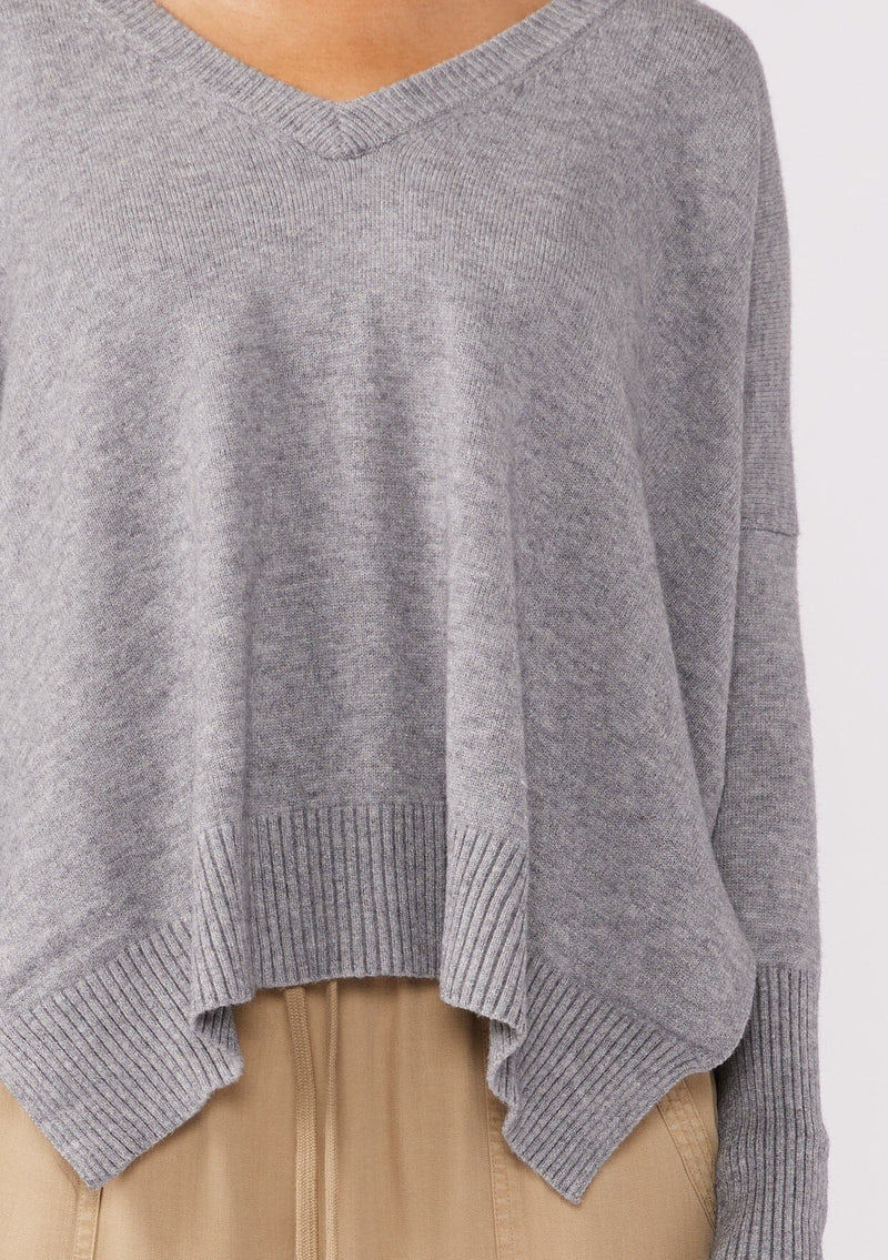 [Color: Lt. Heather Grey] A detailed image of a brunette model wearing a soft and relaxed fit knit sweater. A cozy fall pullover sweater with a boxy silhouette, v neckline, ribbed trim, and side vents. 