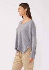 [Color: Lt. Heather Grey] A side facing image of a brunette model wearing a soft and relaxed fit knit sweater. A cozy fall pullover sweater with a boxy silhouette, v neckline, ribbed trim, and side vents. 