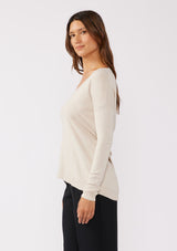 [Color: Bone] A side facing image of a brunette model wearing a soft  knit pullover sweater in ivory. With a comfortable v neckline, long sleeves, and an open back with surplice accent. The perfect basic knit top for any season. 