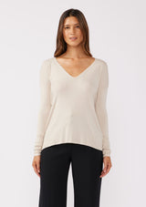 [Color: Bone] A front facing image of a brunette model wearing a soft  knit pullover sweater in ivory. With a comfortable v neckline, long sleeves, and an open back with surplice accent. The perfect basic knit top for any season. 