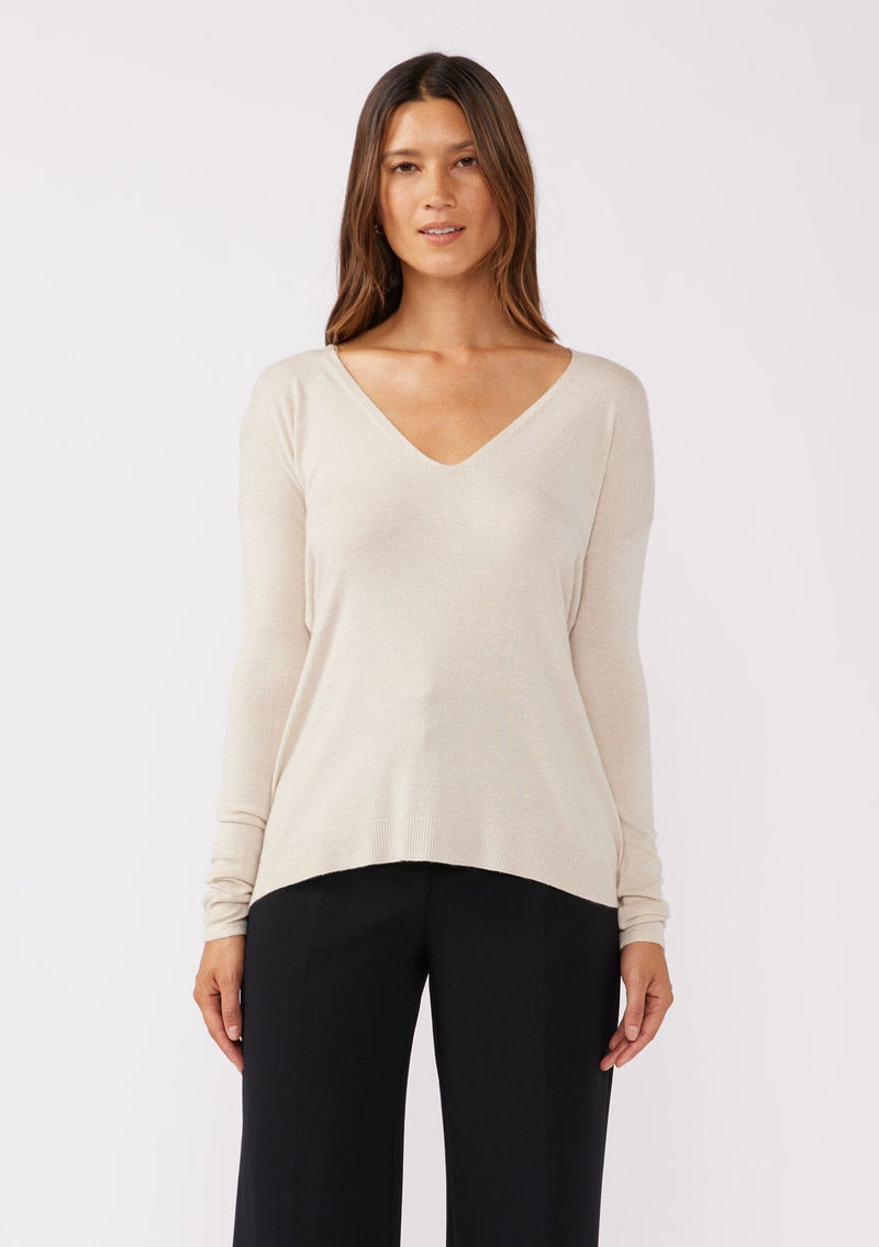 [Color: Bone] A front facing image of a brunette model wearing a soft  knit pullover sweater in ivory. With a comfortable v neckline, long sleeves, and an open back with surplice accent. The perfect basic knit top for any season. 