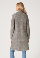 [Color: Taupe/Cream] A back facing image of a blonde model wearing a soft sweater coat in a taupe and cream herringbone pattern. With long sleeves, a button front, side pockets, a mid length hemline, and a notched collar. 