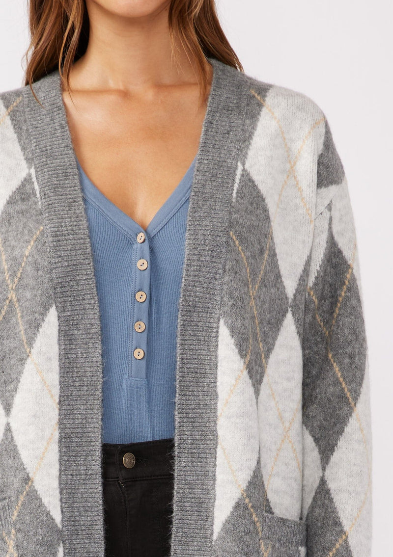 [Color: Charcoal/Grey] A detailed image of a brunette model wearing an ultra-soft mid length cardigan in a grey and light grey argyle plaid pattern. With long sleeves, an open front, and side pockets.