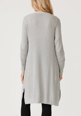 [Color: Heather Silver Grey] A back facing image of a blonde model wearing a light heather grey waffle knit cardigan. A lightweight mid length cardigan sweater with long sleeves, side pockets, and an open front. 